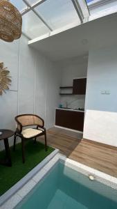 a room with a pool with a chair and a table at Papayas 2 Villa in Yogyakarta
