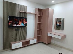 a room with a tv and a wall at Bell Rooms Hotel in Noida
