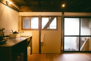 a kitchen with a sink and a sliding glass door at サカナギゲストハウス in Nagano