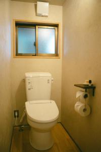 a bathroom with a white toilet with a window at サカナギゲストハウス in Nagano