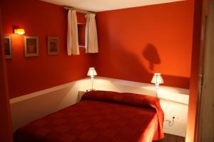 a red bedroom with a bed and two lamps at Apartamentos Rincón del Puerto in San Vicente de la Barquera