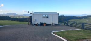 a small shed with a dog sitting in front of it at Bream Bay Views in Ruakaka