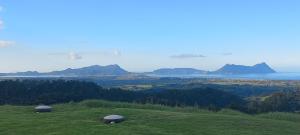 a green hill with two domes on top of it at Bream Bay Views in Ruakaka