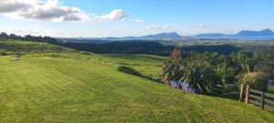 a green grassy hill with a fence on it at Bream Bay Views in Ruakaka