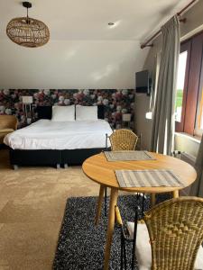 a bedroom with a bed and a table and chairs at B&B de grote Zeearend in Aardenburg