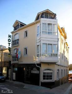 um edifício branco alto na esquina de uma rua em Hotel Viento del Norte em Porto de Espasante