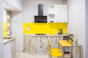 a kitchen with yellow and white cabinets and a table at Apartment on Pekarska street зі світлом! in Lviv