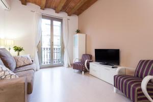 a living room with a tv and a couch and chairs at Casa Cosi Letamendi in Barcelona