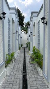 a cobblestone alley with white buildings and plants at Papayas 2 Villa in Yogyakarta