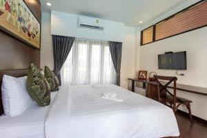 a bedroom with a large white bed and a desk at The La-Ngu Boutique in Langu