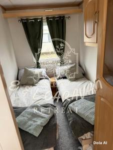 two beds in a small room with a window at E & L Caravan Retreat in Ingoldmells