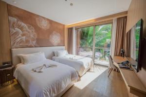 a hotel room with two beds and a window at Riverton Hotel in Samut Songkhram