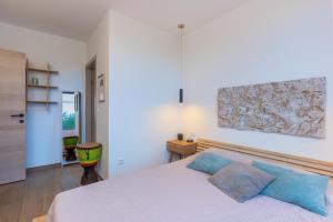 a bedroom with a white bed with blue pillows at Villa Elementa Krk - Luxury Four Elements Experience in Krk +45 photos