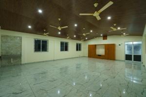 a large room with ceiling fans and a stone floor at Gayathri Nest in Udupi