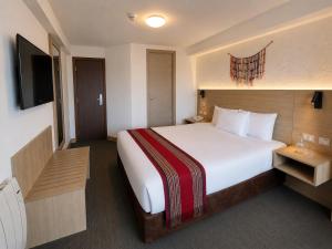 a hotel room with a large bed and a television at Ecoterra Essentials San Blas in Cusco