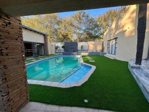 a backyard with a swimming pool and green grass at Jul Rick House Guesthouse in Sandton