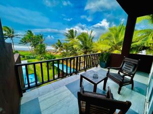 a balcony with a view of the ocean and palm trees at Villa Ocean Dew in Galle