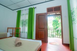 a bedroom with green curtains and a bed and a door at Zenvora Rainforest Villa in Deniyaya