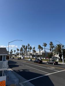 a street with cars driving down a road with palm trees at Two Bedroom Beach Apartment in Sunset Beach