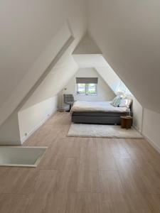 a attic bedroom with a bed and wooden floors at LITTLENEIGHBOUR in Pingjum