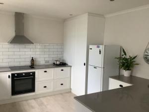 a kitchen with white appliances and a white refrigerator at Relaxing Beach Side House in Porirua +2 photos