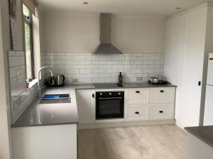 a white kitchen with a sink and a stove at Relaxing Beach Side House in Porirua
