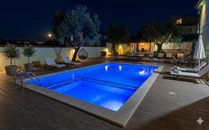 ein Swimmingpool in einem Garten bei Nacht in der Unterkunft Button Aparthotel in Dobra Voda