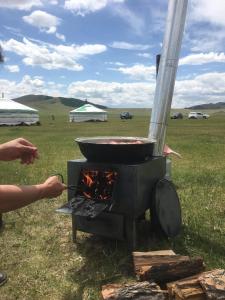a person cooking food in a bbq on a grill at Mongolian traditional Ger accomodation in Narst