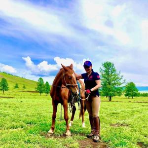 a woman standing next to a horse in a field at Mongolian traditional Ger accomodation in Narst