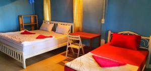 a bedroom with two beds and a table and a chair at Longbeach Kohphayam in Ko Phayam