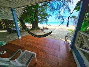a porch with a hammock and a view of the beach at Longbeach Kohphayam in Ko Phayam