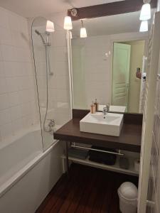 a bathroom with a sink and a tub and a mirror at Cottage Mansart piscine tout équipé in Chaveignes +14 photos