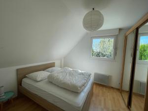 a bedroom with a bed with white sheets and a window at Maisons avec terrasse et parking in Colmar