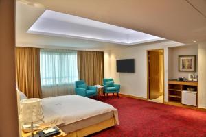a hotel room with a bed and a desk and chairs at Dhaka Regency Hotel & Resort in Joār Sāhāra