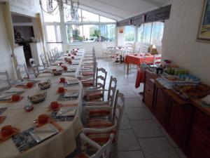 een lange rij tafels in een restaurant met rode tafelkleden bij Au Relais Provencal in Bagnols-en-Forêt