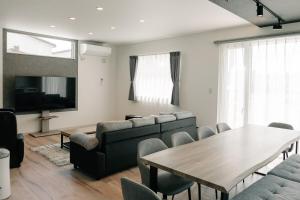 a living room with a couch and a table and chairs at AOI Villa Biei in Biei