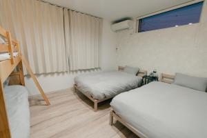 a small room with two beds and a window at AOI Villa Biei in Biei