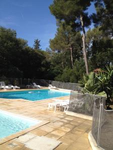 uma piscina com mesas e cadeiras ao lado em Hôtel De La Mer em La Croix-Valmer