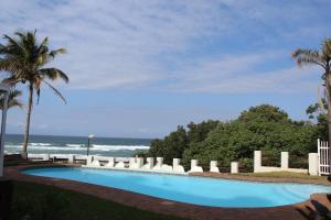 a swimming pool with chairs and the ocean at Dumela Margate Flat No 17 in Margate