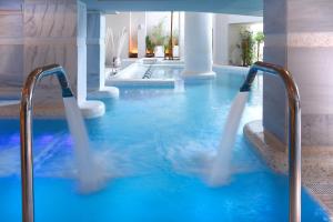a swimming pool with blue water in a building at Royal Hideaway Sancti Petri in Chiclana de la Frontera