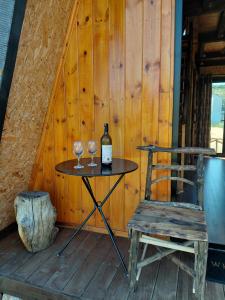 a table with a bottle of wine and a chair at Cozy Lakefront Cabin - Myselim in Shkodër