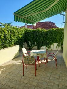 a table and chairs under a green umbrella at Apartman Zablace in Zablaće +5 photos