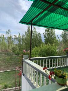 a green umbrella on top of a balcony at Larikha stay chumpa in Leh +5 photos