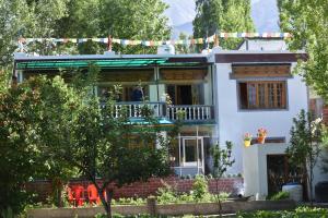 a white house with a porch and a balcony at Larikha stay chumpa in Leh