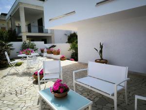 a patio with white chairs and tables and flowers at b&b Bellavista in Castro di Lecce