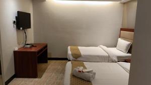 a hotel room with two beds and a television at Cherry Midtown Hotel in Bahac-bahac