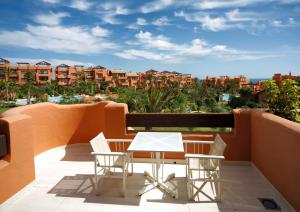 a white table and chairs on a balcony with buildings at Royal Hideaway Sancti Petri in Chiclana de la Frontera