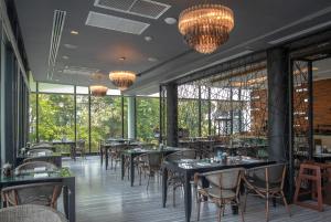a restaurant with tables and chairs and chandeliers at Z Through By The Zign in North Pattaya