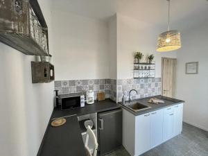 a small kitchen with a sink and a microwave at Víkend Apartmanok in Révfülöp