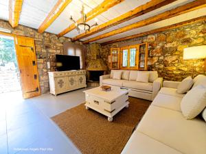 a living room with white furniture and a stone wall at Kefalonian Luxury Villas in Kástron
